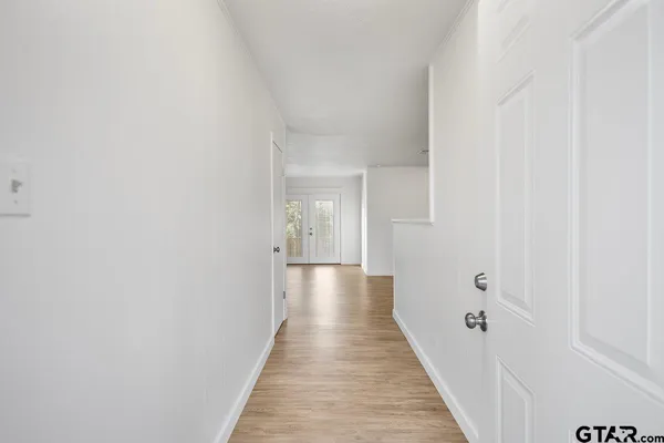 a view of a hallway with wooden floor and a bathroom