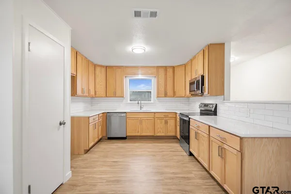 a large kitchen with stainless steel appliances granite countertop a sink and cabinets