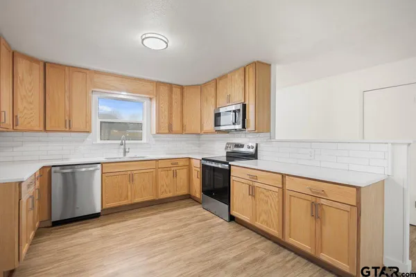 a kitchen with white cabinets appliances and a window