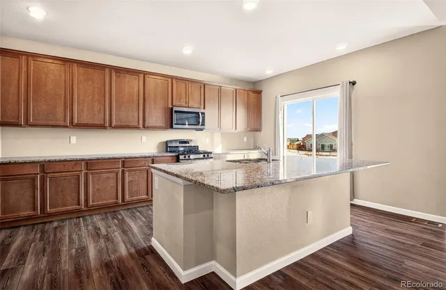 a kitchen with granite countertop wooden floors a stove and a sink