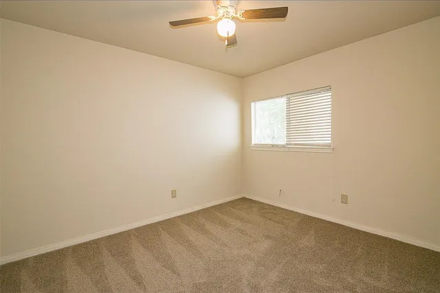 an empty room with a chandelier fan and windows