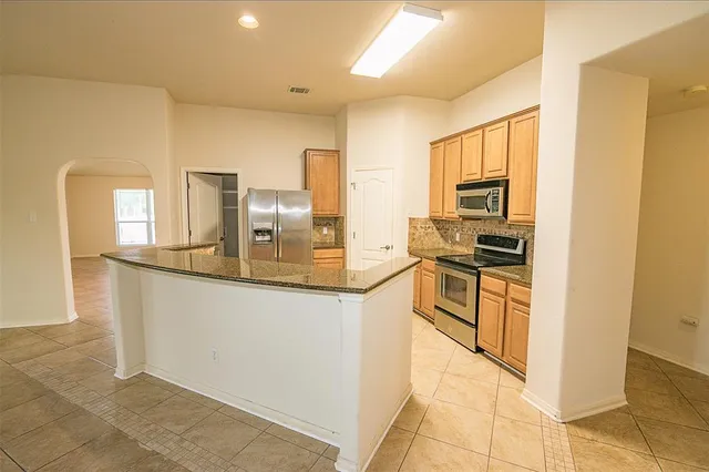 a kitchen with stainless steel appliances granite countertop a refrigerator and a stove