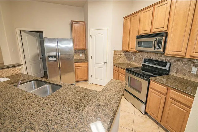 a kitchen with granite countertop a refrigerator and a sink