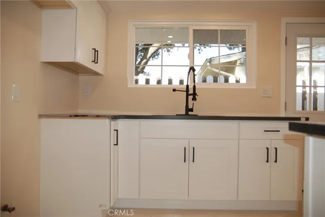 a kitchen with white cabinets and window