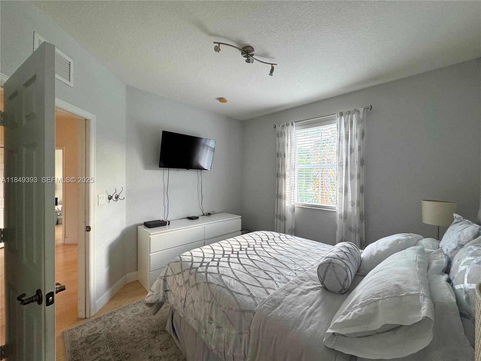11575 Southwest 138th Avenue Miami, FL 33186 - Photo 18 of 23 a bedroom with a bed and a flat tv screen on dresser
