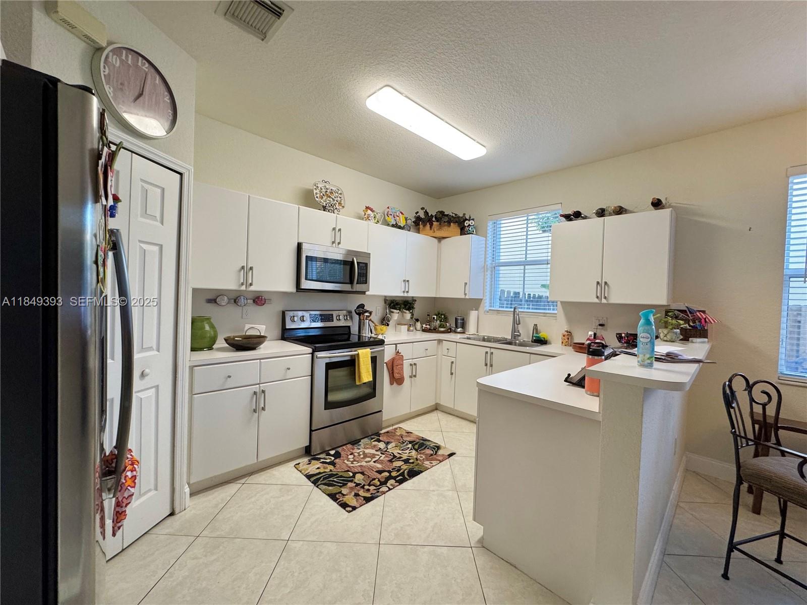 11575 Southwest 138th Avenue Miami, FL 33186 - Photo 6 of 23 a kitchen with stainless steel appliances a refrigerator stove microwave and white cabinets