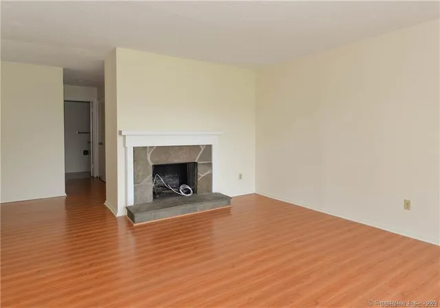 a view of an empty room with wooden floor and a fireplace