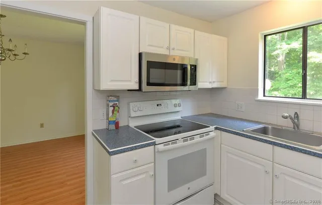 a kitchen with granite countertop white cabinets appliances and a window