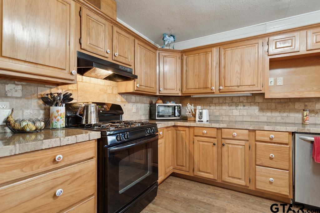 301 Bascom Road Whitehouse, TX 75791 - Photo 18 of 31 a kitchen with granite countertop wooden cabinets and a stove top oven