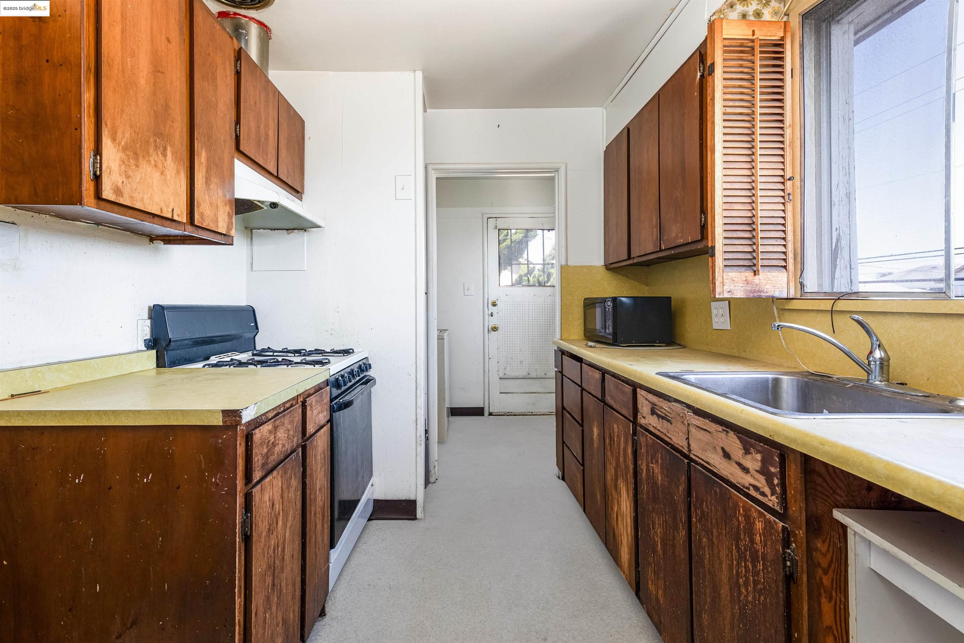 1427 65th Avenue Oakland, CA 94621 - Photo 10 of 13 a kitchen with stainless steel appliances granite countertop a sink and a stove
