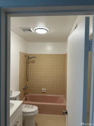 a bathroom with a granite countertop bathtub shower sink vanity and toilet
