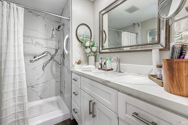 a bathroom with a granite countertop sink a mirror and shower