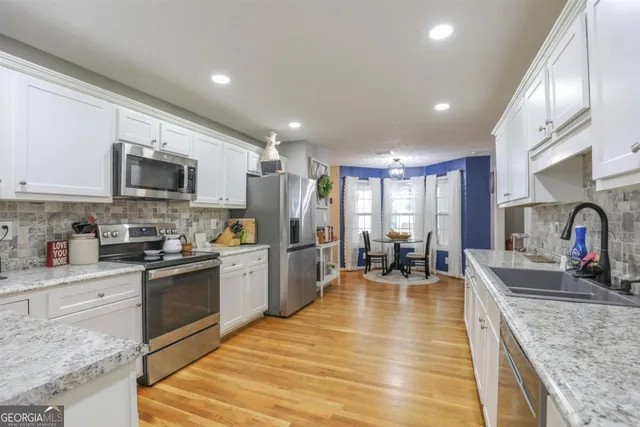 a large kitchen with granite countertop lots of counter space dining table and stainless steel appliances