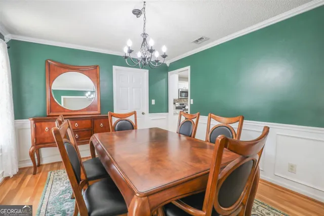 a view of a dining room with furniture a chandelier and wooden floor