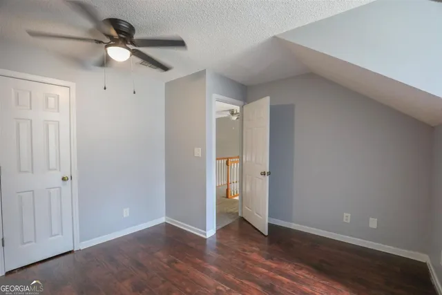 an empty room with wooden floor ceiling fan and windows