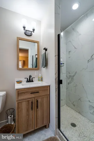 a bathroom with a granite countertop sink a mirror and shower