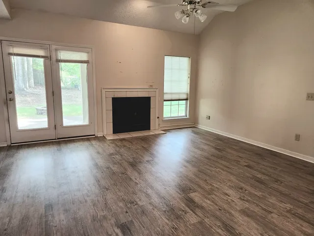 an empty room with wooden floor fireplace and windows