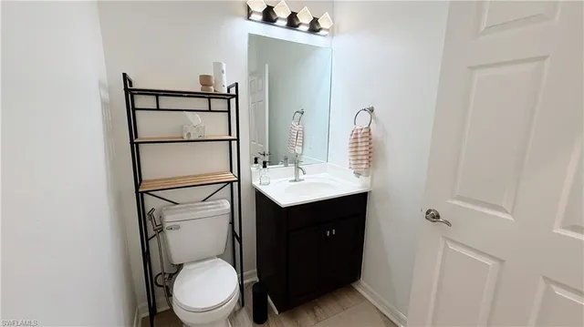 a bathroom with a toilet sink vanity granite and mirror