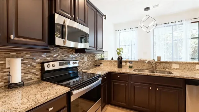 a kitchen with granite countertop a sink stove and microwave