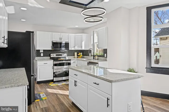 a kitchen with kitchen island granite countertop a sink appliances and cabinets