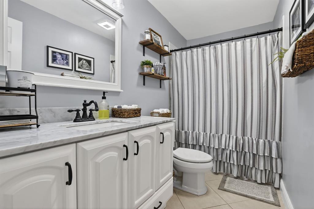 11611 Southwest 52nd Street Cooper City, FL 33330 - Photo 35 of 45 a bathroom with a granite countertop sink a toilet and a shower curtain