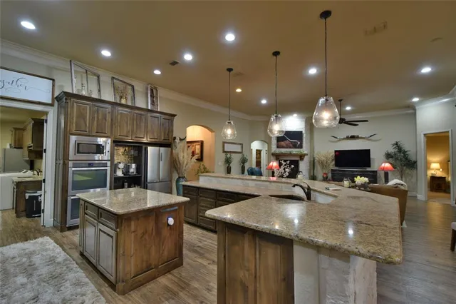 a living room with stainless steel appliances kitchen island granite countertop furniture and a wooden floor