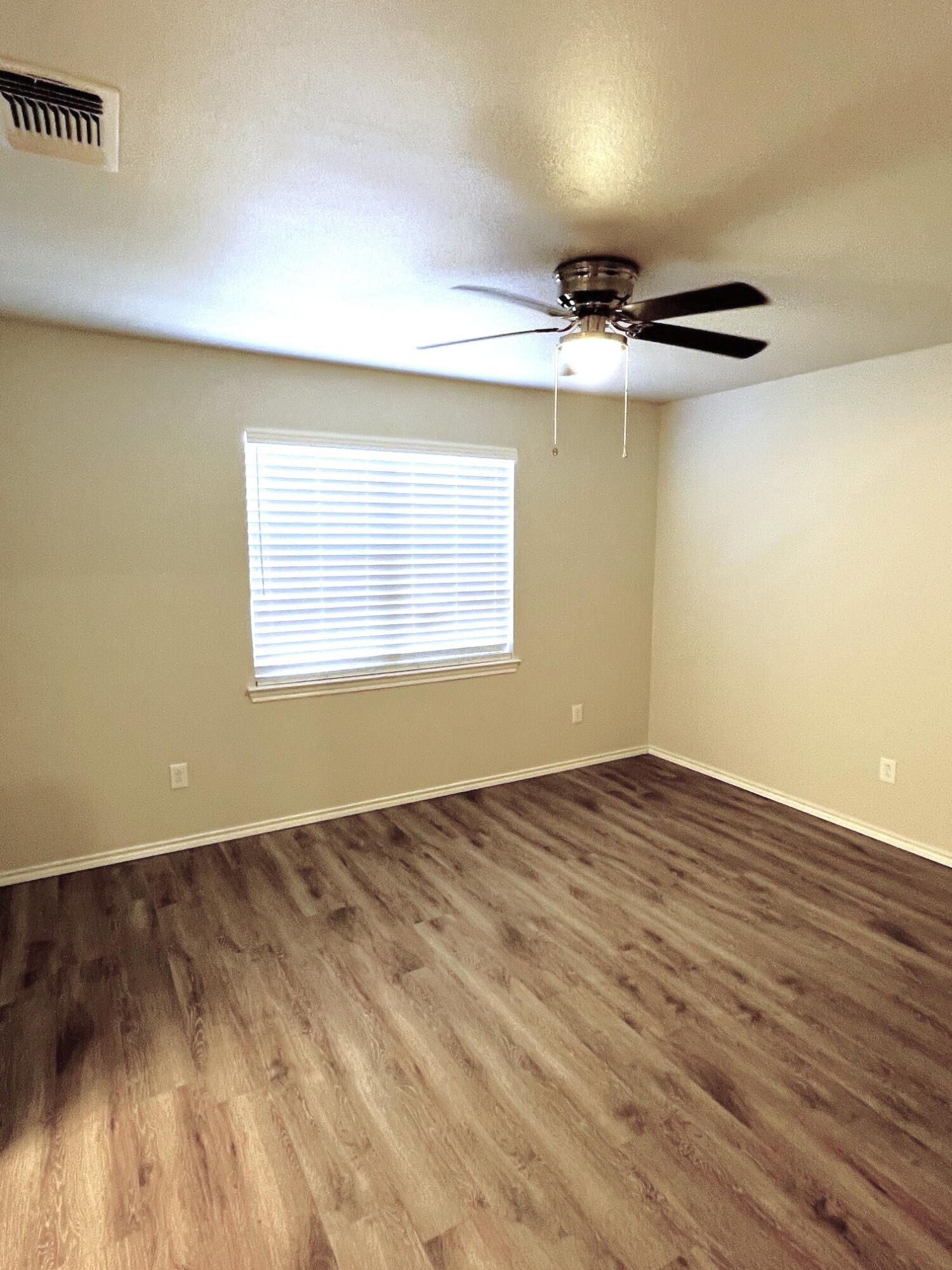 7504 Avenue West, Unit A Lubbock, TX 79423 - Photo 13 of 17 an empty room with wooden floor chandelier and windows