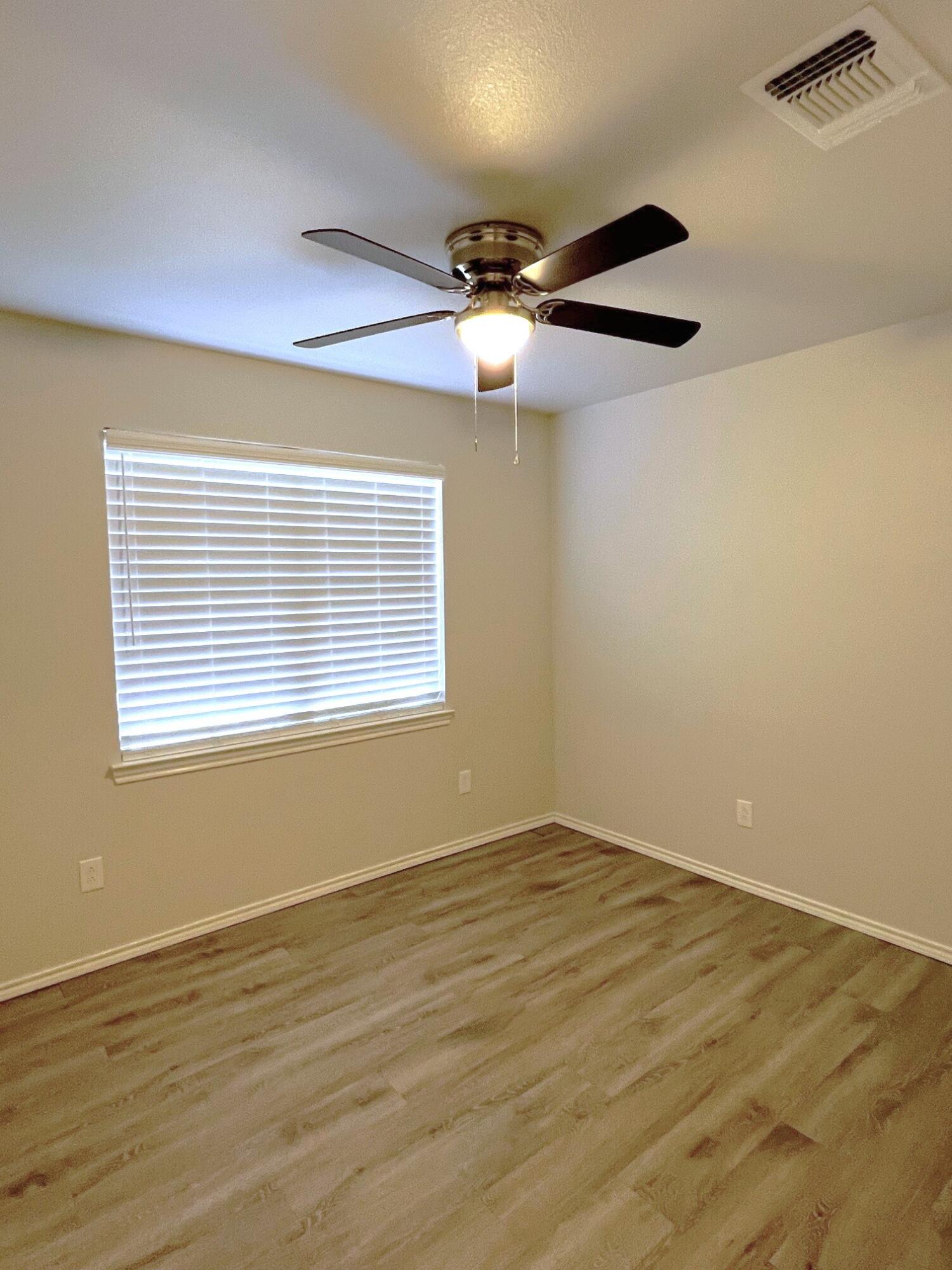 7504 Avenue West, Unit A Lubbock, TX 79423 - Photo 14 of 17 a view of an empty room with wooden floor and a window
