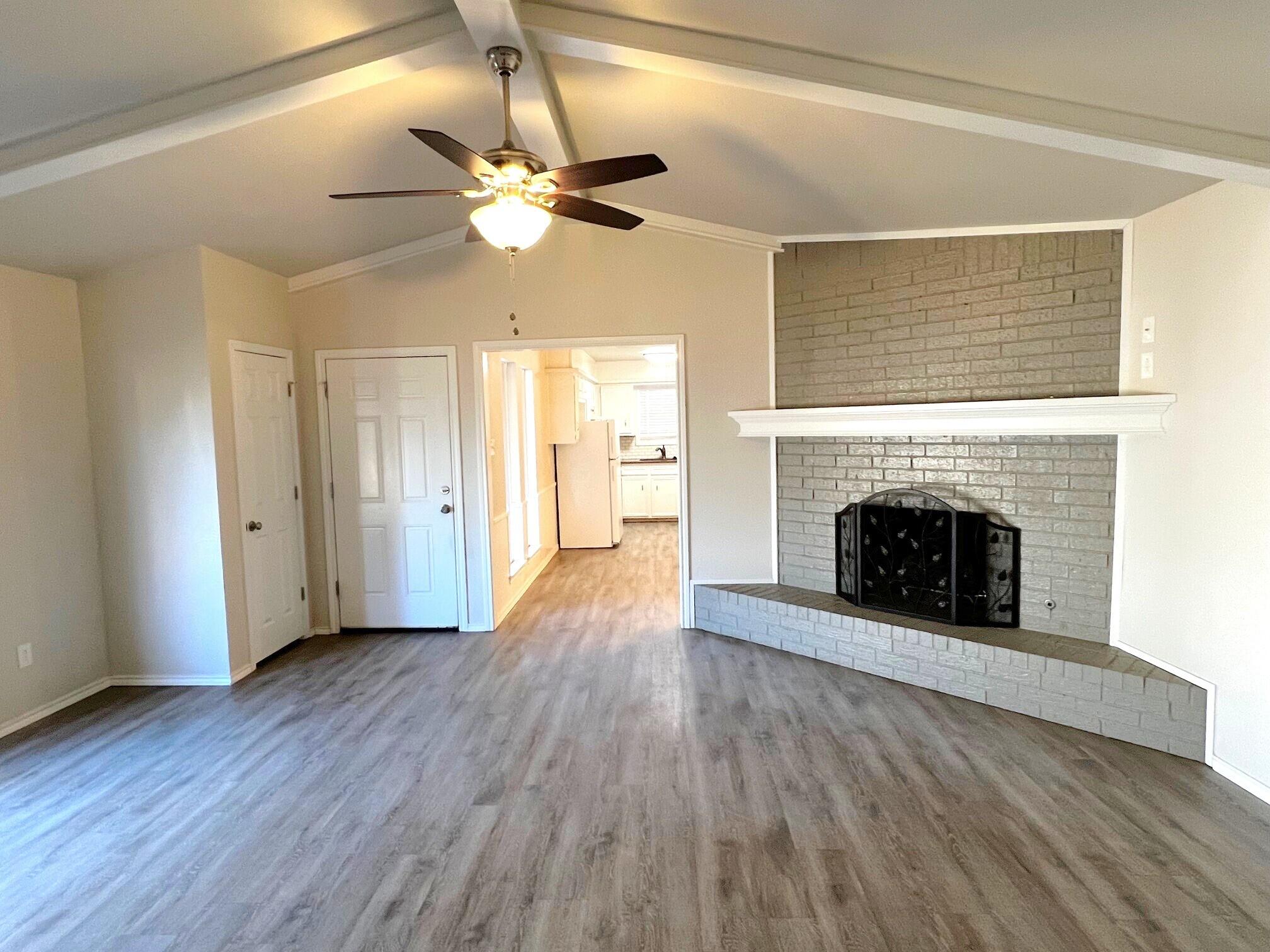 7504 Avenue West, Unit A Lubbock, TX 79423 - Photo 2 of 17 a view of an empty room with wooden floor fireplace and a window