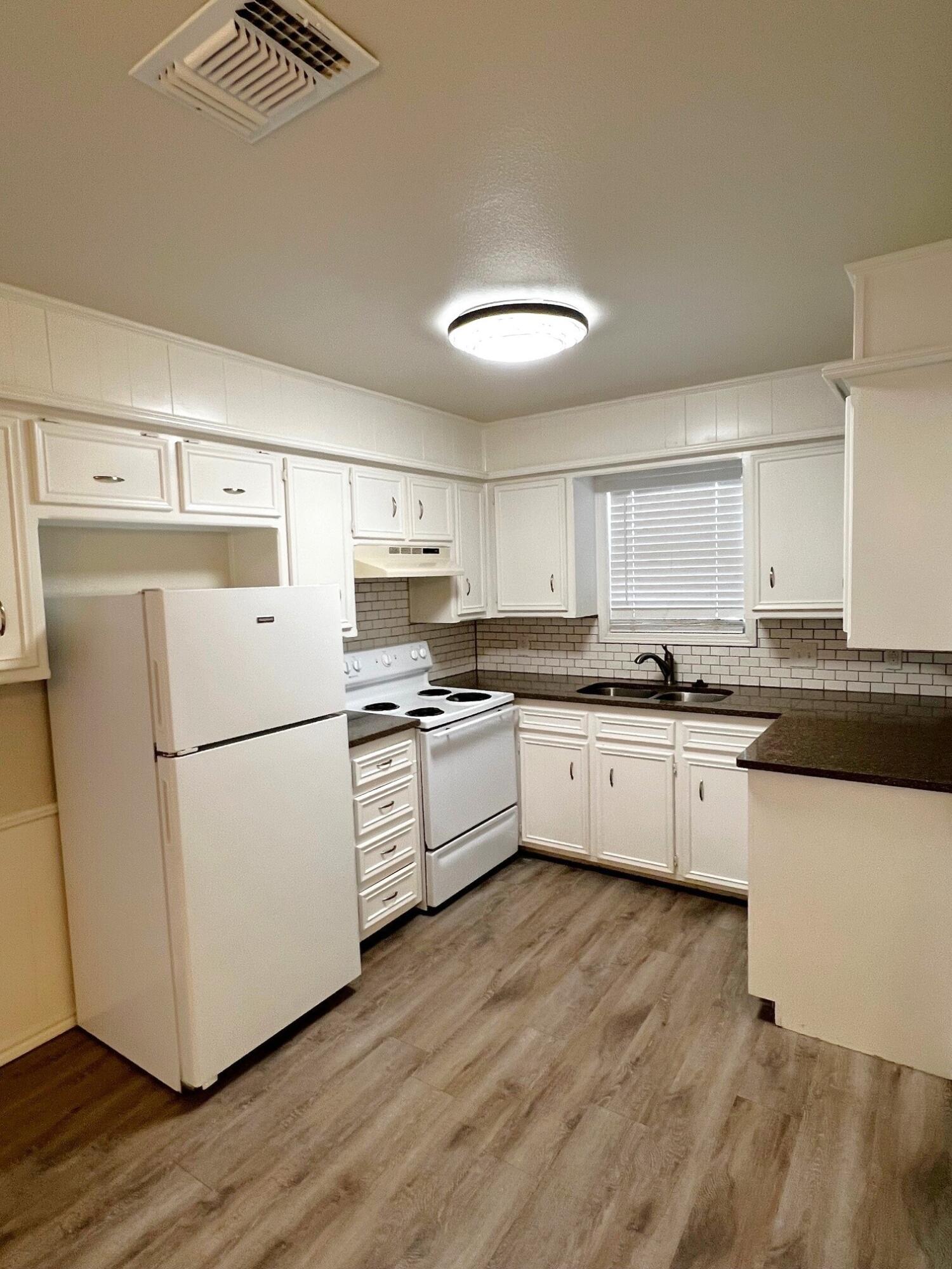 7504 Avenue West, Unit A Lubbock, TX 79423 - Photo 3 of 17 a kitchen with granite countertop white cabinets and white appliances