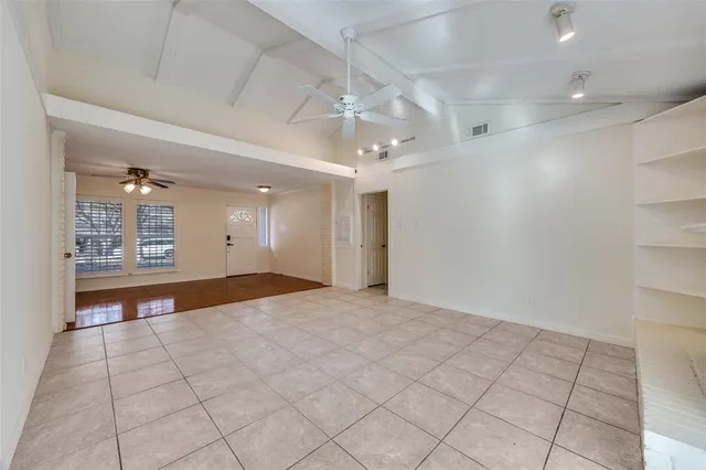 an empty room with kitchen and chandelier fan