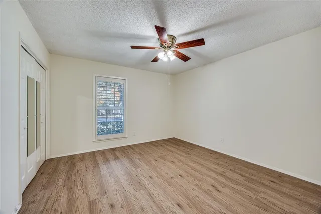 an empty room with wooden floor fan and windows