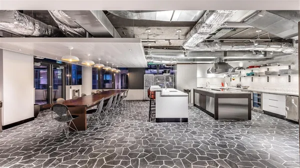 a dining hall with stainless steel appliances kitchen island granite countertop a table chairs and a refrigerator