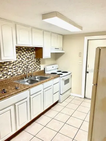 a kitchen with white cabinets a sink a stove a refrigerator and white cabinets