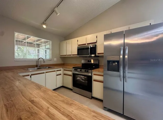 a kitchen with stainless steel appliances granite countertop a stove a sink and a refrigerator
