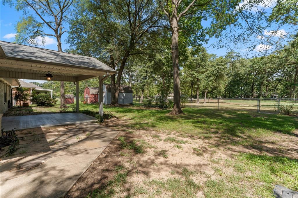 116 Meadowood Road Enchanted Oaks, TX 75156 - Photo 8 of 37 Spacious backyard featuring a covered patio, a shed, mature trees, and a chain-link fence