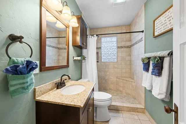 a bathroom with a granite countertop sink toilet and shower