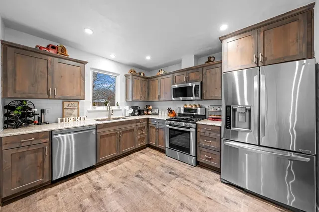 a kitchen with granite countertop a refrigerator stove top oven and sink