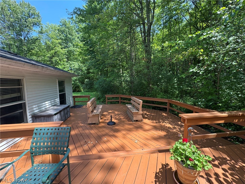 8201 Orchard Road Painesville, OH 44077 - Photo 40 of 45 Expansive wood-finish deck with integrated seating and perimeter railing, surrounded by mature trees