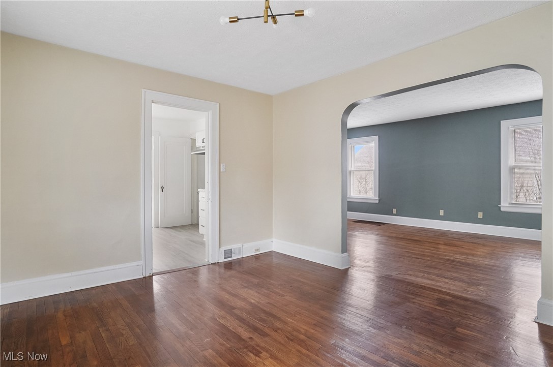 646 Brittain Road Akron, OH 44305 - Photo 10 of 36 Empty room featuring baseboards, visible vents, arched walkways, and wood finished floors