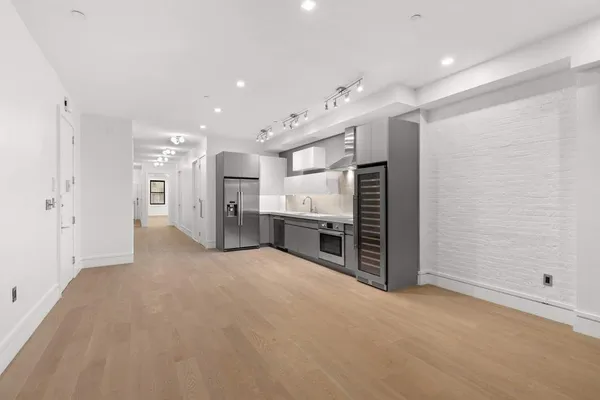 a large white kitchen with stainless steel appliances granite countertop a sink and dishwasher a stove with wooden floor