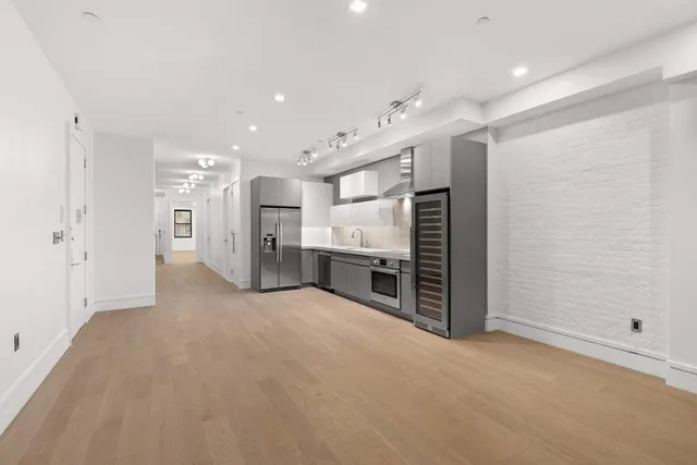 a large white kitchen with stainless steel appliances granite countertop a sink and dishwasher a stove with wooden floor