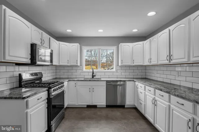 a kitchen with stainless steel appliances granite countertop white cabinets granite counter tops and a window