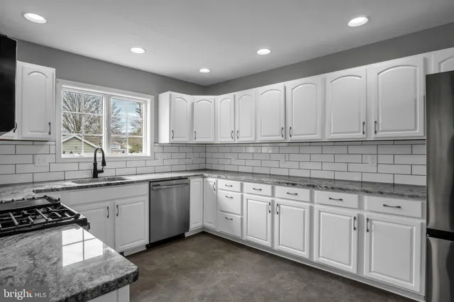 a kitchen with white cabinets sink and appliances