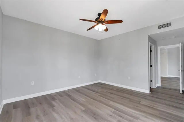 an empty room with wooden floor and ceiling fan