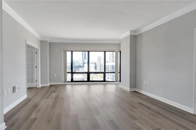 a view of an empty room with wooden floor and a window