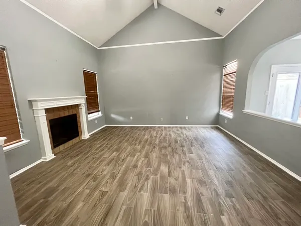 a view of empty room with wooden floor and fireplace