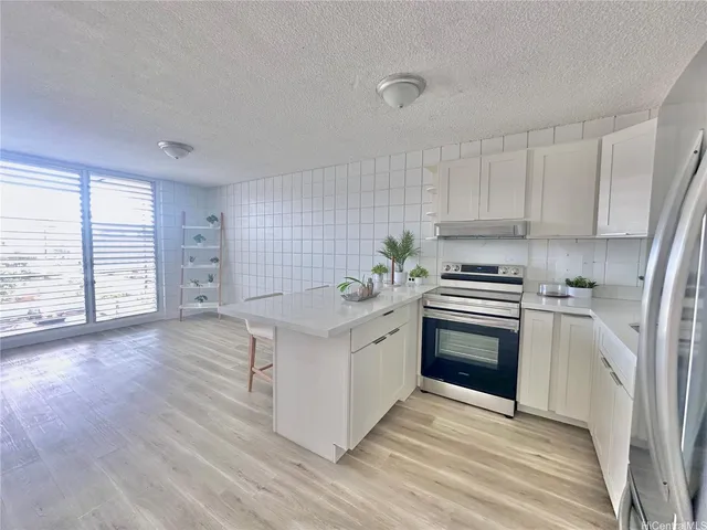 a kitchen with stainless steel appliances a sink a stove a refrigerator cabinets and wooden floor