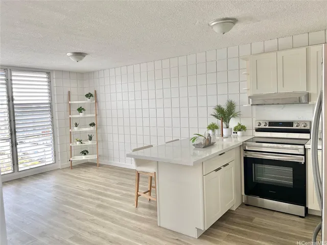 a kitchen with stainless steel appliances granite countertop a refrigerator a sink a stove and white cabinets