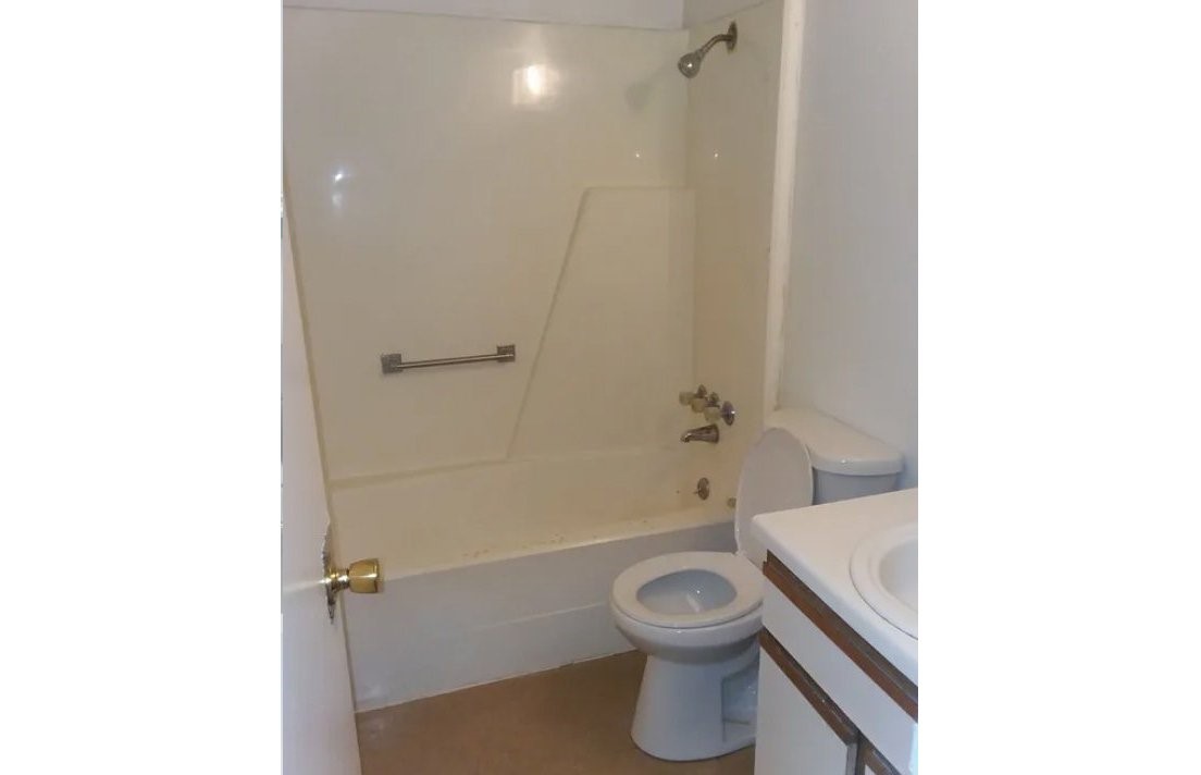 208 East Wells Street Madisonville, TX 77864 - Photo 2 of 7 a bathroom with a toilet and a shower